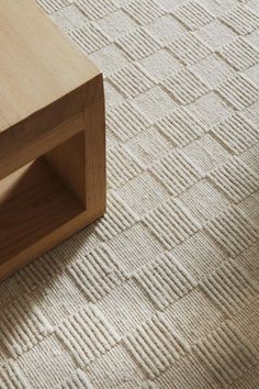 a close up of a coffee table on a carpeted floor with a wooden shelf