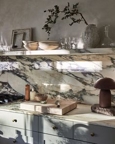 a kitchen with marble counter tops and white cupboards filled with dishes on top of them