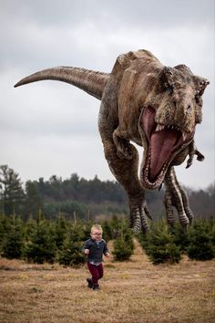 a young boy standing in front of an adult dinosaur with its mouth open and it's teeth wide open