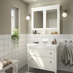 a white bathroom with black and white tile on the floor, sink, mirror and towel rack