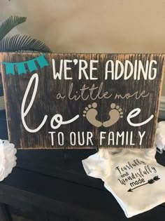 a wooden sign that says we're adding a little more love to our family