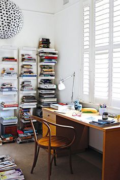 a room with a desk, chair and bookshelf full of books in it