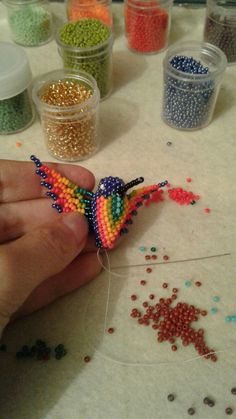 a person is making beaded birds out of beads