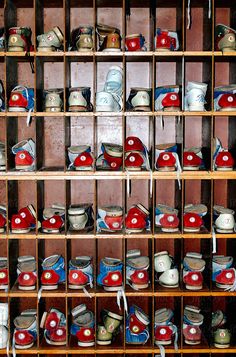 many pairs of shoes are on shelves in a storage area with wooden racks holding them