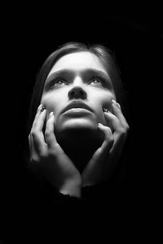 a black and white photo of a woman's face with hands on her cheeks