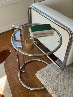 a glass table with books on it in a living room next to a white chair