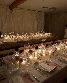 a long table is set with candles and flowers in glass vases on the tables