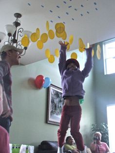 two people are jumping in the air with balloons and confetti on their heads