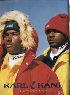 two black men wearing red and yellow jackets with fur hoods on their heads, both looking at the camera