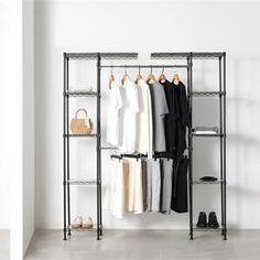 an iron rack with clothes and shoes hanging on it in front of a white wall