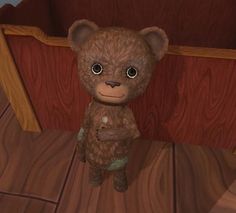 a brown teddy bear sitting on top of a wooden floor