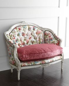 an old chair with a red pillow on it in front of a white paneled wall