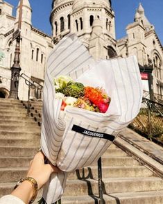 someone holding up a bag with food in front of a castle like building on top of some steps