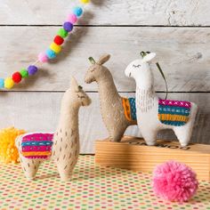 two llamas are sitting on a table with pom - poms around them