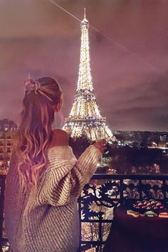 a woman standing in front of the eiffel tower looking at her cell phone