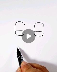 a hand holding a marker writing the word e on a piece of paper with glasses drawn on it