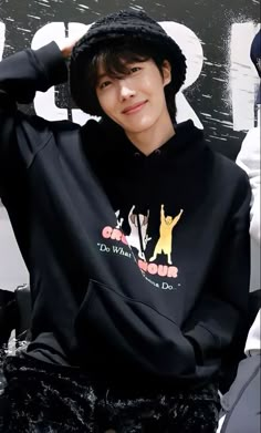 a young man wearing a black hoodie sitting on top of a white counter next to a sign