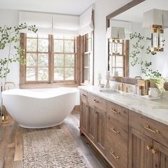 a bathroom with a large white bathtub next to a wooden vanity and mirror above it