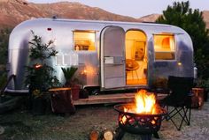 a camper trailer is lit up by the fire pit