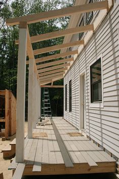 a house being built with wood planks on the front porch and covered in white paint