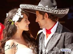 a man and woman dressed up in mexican style clothing, standing close to each other