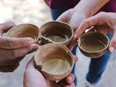 three people holding small bowls filled with liquid