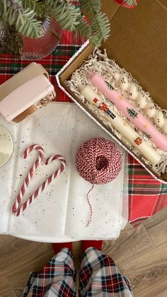 a box filled with candy canes next to a christmas tree and other holiday decorations