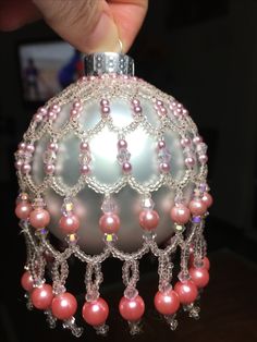 a hand is holding an ornament with pearls and beads