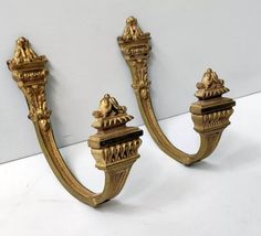 two gold colored wall sconces on a white surface