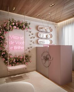 a room with pink and white decor on the walls, flowers hanging from the ceiling