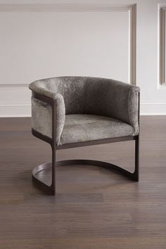 a gray chair sitting on top of a hard wood floor next to a white wall