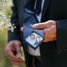 a man in a black suit holding a blue photo frame with a couple on it