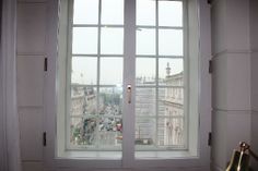 an open window in the corner of a room with a view of a city street