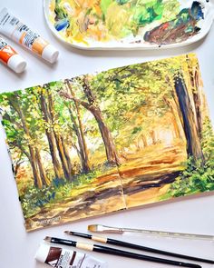 an artist's palette, watercolors, and paintbrushes on a table