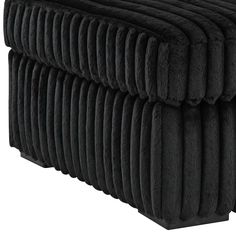 an upholstered black ottoman with pleated edges