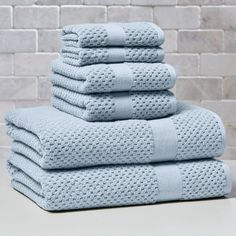 stack of folded blue towels in front of a brick wall with white bricks on it