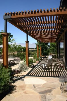 an outdoor covered patio area with chairs and tables on the outside, surrounded by greenery