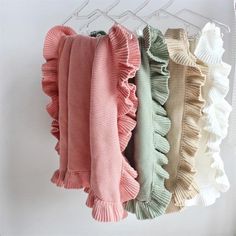 several sweaters hanging on a clothes rack in different colors and sizes, all with ruffles