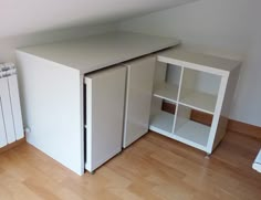 a small white cabinet sitting next to a radiator in a room with hard wood floors