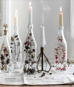 bottles with flowers and candles in them sitting on a table