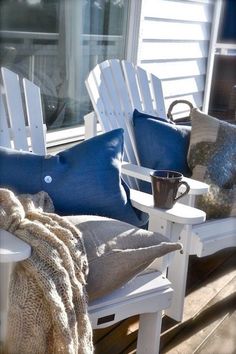 two white adiron chairs sitting on top of a wooden deck