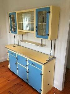 an old fashioned blue and yellow cabinet with glass doors on the front, in a room with hard wood floors