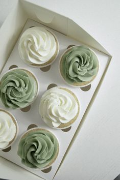 four cupcakes with green frosting in a box