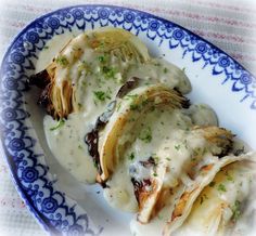 a blue and white plate topped with food covered in gravy on top of a table