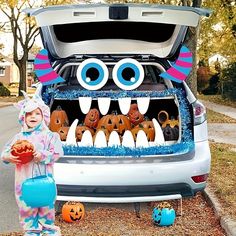 a child standing in front of a car with its trunk open and monster teeth on it