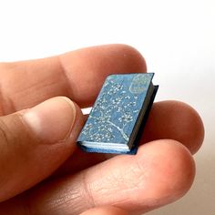 a miniature book in the palm of someone's hand