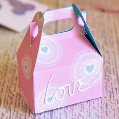 a small pink box with scissors in it sitting on a table next to some cards