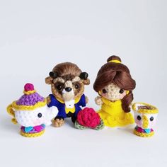 three crocheted toy animals dressed as princess and beast, one holding a tea cup