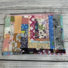 a multicolored patchwork wallet sitting on top of a wooden table