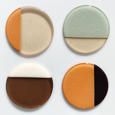 four plates with different colors and shapes on each one, including brown, white, and green